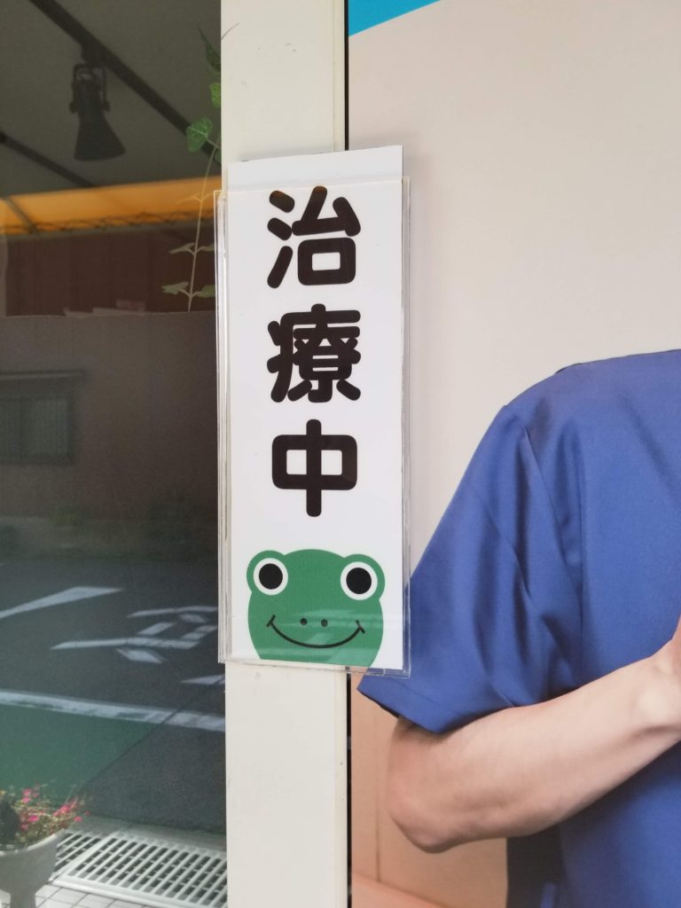 入口に掲示されているカエルのイラスト入り治療中のプレート